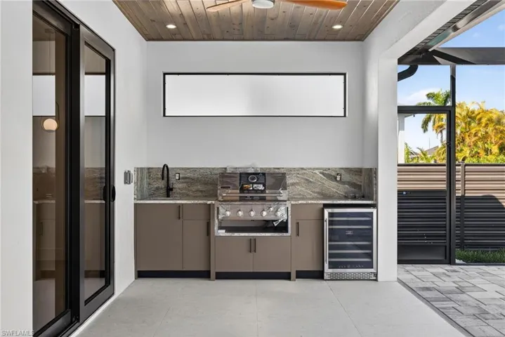 View of patio featuring area for grilling, a ceiling fan, and beverage cooler