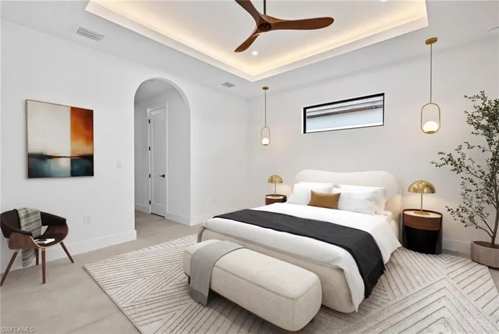 Bedroom with arched walkways, a raised ceiling, a ceiling fan, and concrete flooring