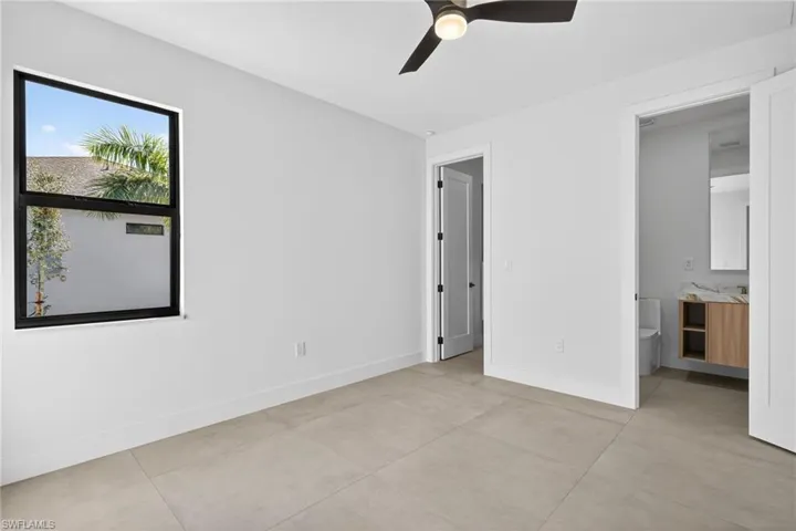 Unfurnished bedroom with ceiling fan and connected bathroom