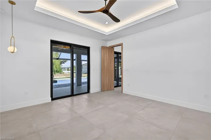 Empty room featuring a tray ceiling and ceiling fan