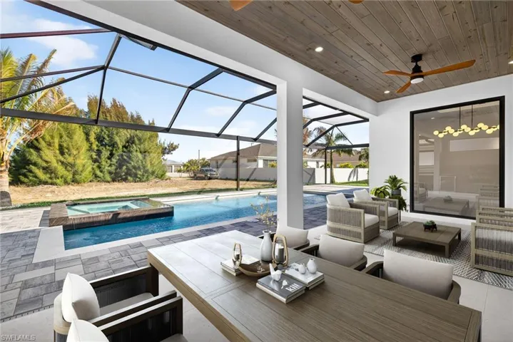 Relaxing pool / spa featuring a sunroom, a patio area, glass enclosure, and an outdoor living / dining area