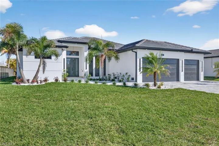 View of front of home with stucco siding, a front lawn, driveway, and a garage