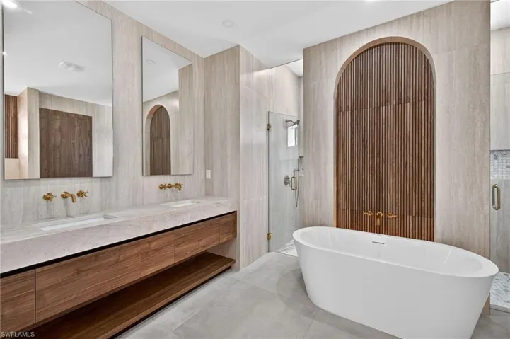 Bathroom with a stall shower, tile walls, double vanity, and a soaking tub