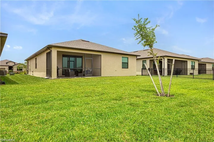 Expansive green lawn with a screened-in patio featuring a concrete slab and a stucco exterior