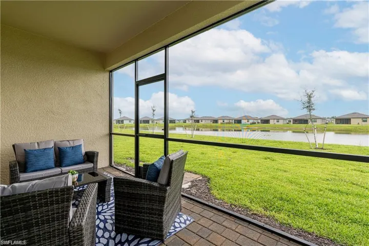 Screened lanai featuring a textured wall, brick paver flooring, and dark-framed screening