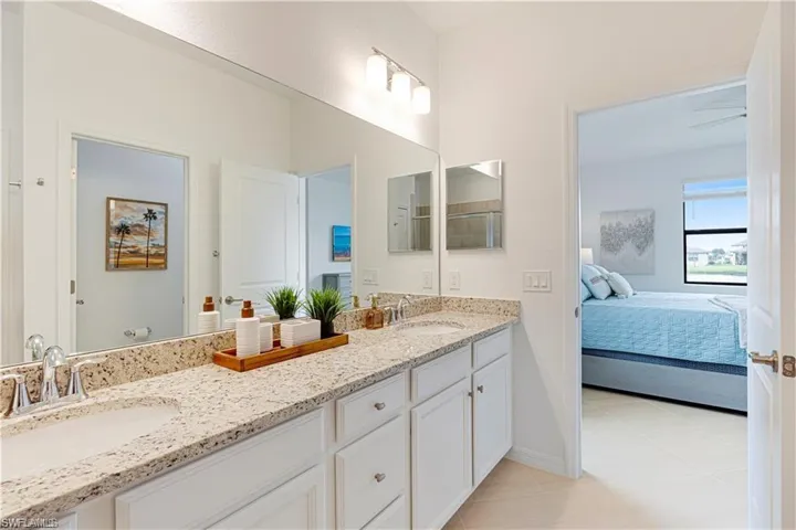 Spacious bathroom featuring a dual-sink vanity with a light-toned speckled countertop, integrated white sinks, and chrome faucets