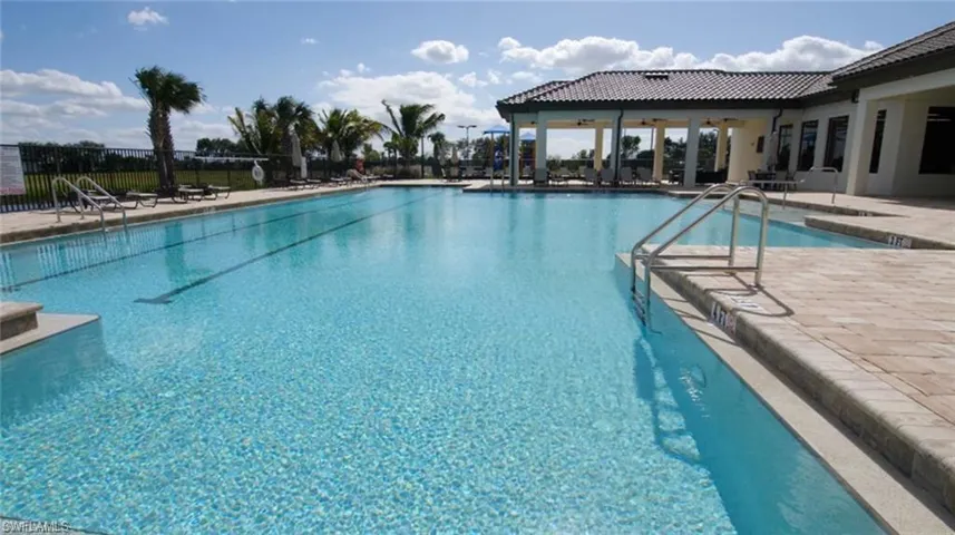 Expansive outdoor swimming pool with lane markers, bordered by light-toned paver decking