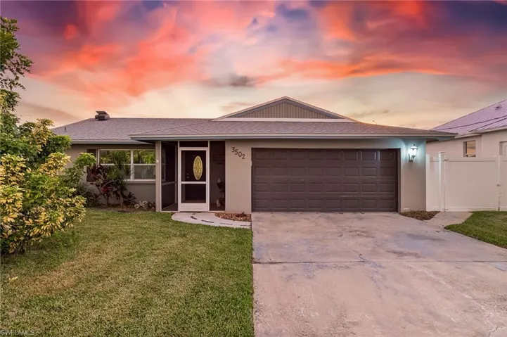 Ranch-style house with an attached garage, a front yard, driveway, stucco siding, and roof with shingles