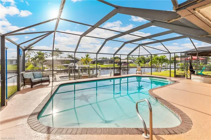 Swimming pool featuring a water view, a sunroom, glass enclosure, and a patio area