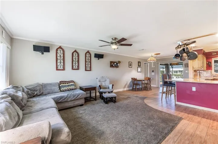 Living room with ornamental molding, light wood-type flooring, and a ceiling fan