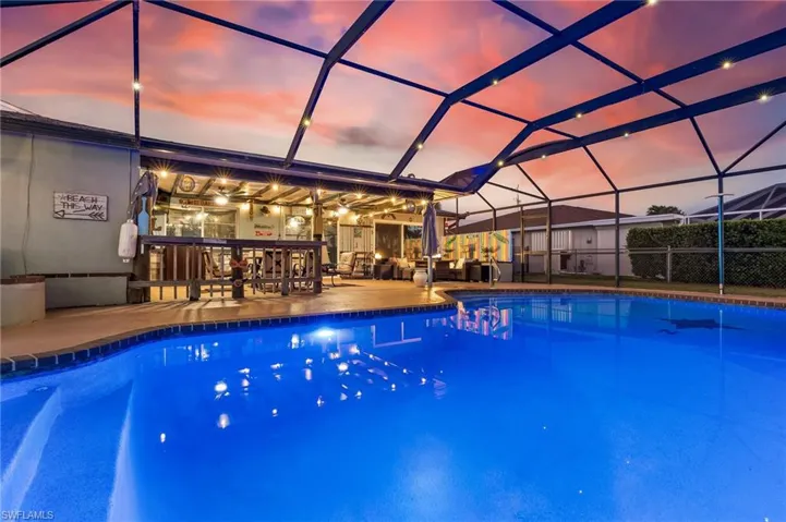 Pool at dusk featuring an outdoor pool, a sunroom, and glass enclosure