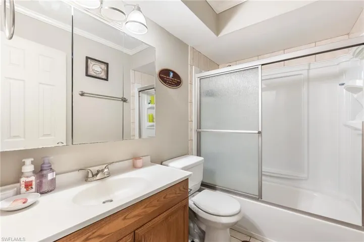 Full bathroom with vanity, bath / shower combo with glass door, ornamental molding, and light tile patterned flooring