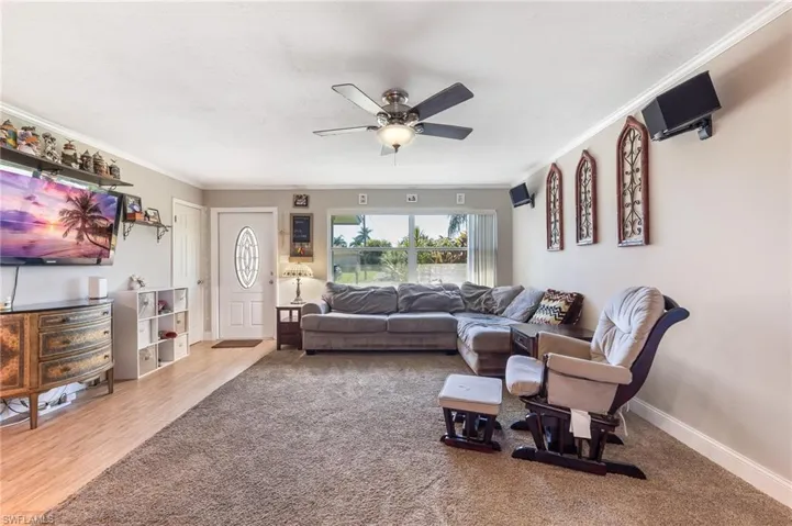 Living room with crown molding, a ceiling fan, light colored carpet, and light wood-style floors