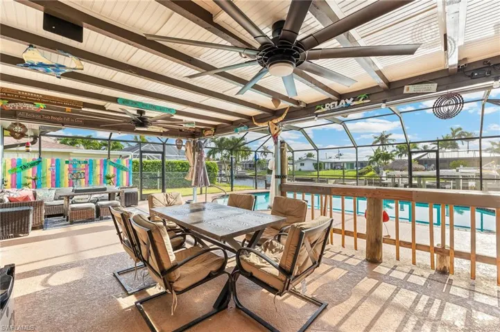 View of patio / terrace with glass enclosure, a water view, ceiling fan, and outdoor dining area