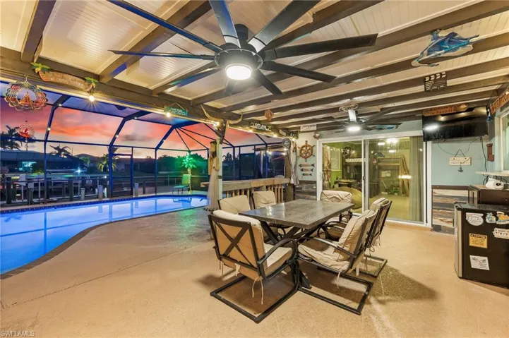 View of patio with an outdoor pool, glass enclosure, a ceiling fan, a sunroom, and outdoor dining space