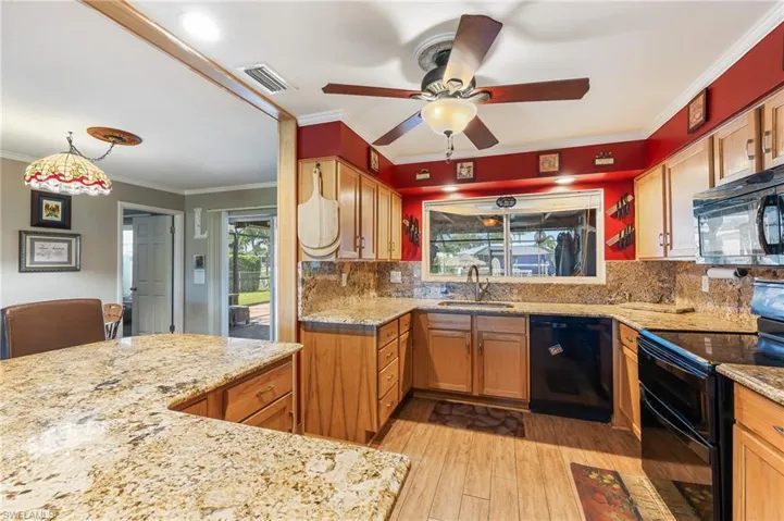 Kitchen with black appliances, crown molding, decorative backsplash, light stone counters, and light wood-style floors