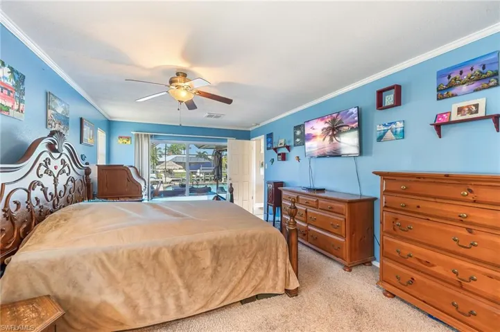 Bedroom featuring light colored carpet, crown molding, and a ceiling fan