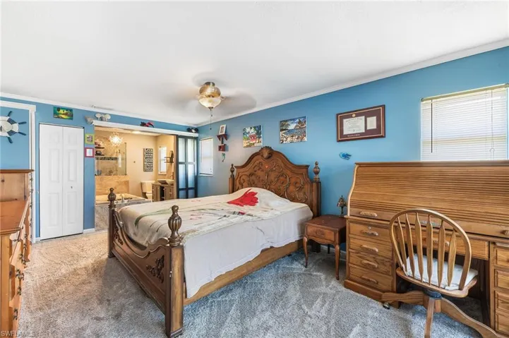 Bedroom with ornamental molding, carpet, ceiling fan, and ensuite bath