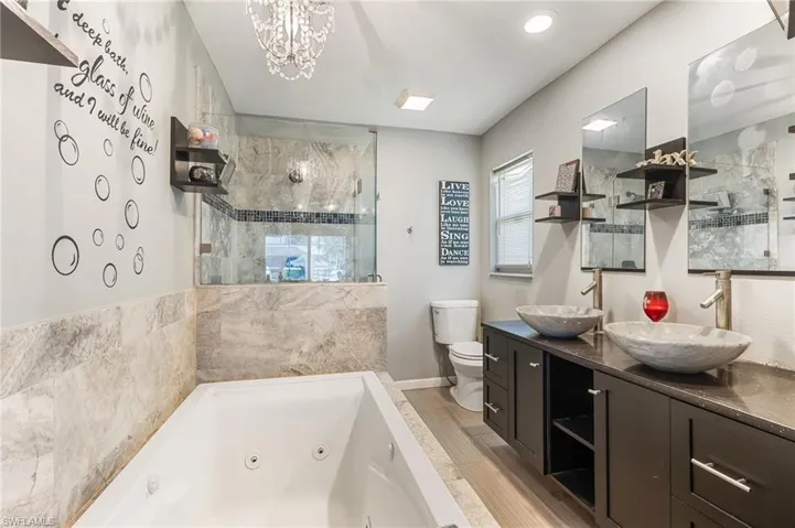 Bathroom with double vanity, a stall shower, a whirlpool tub, and plenty of natural light