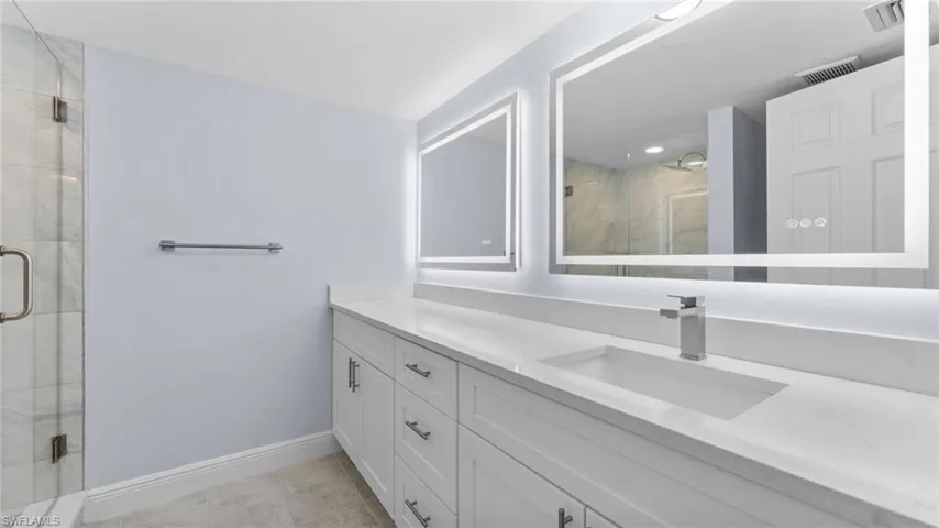 Full bath featuring vanity, a stall shower, and light tile patterned flooring
