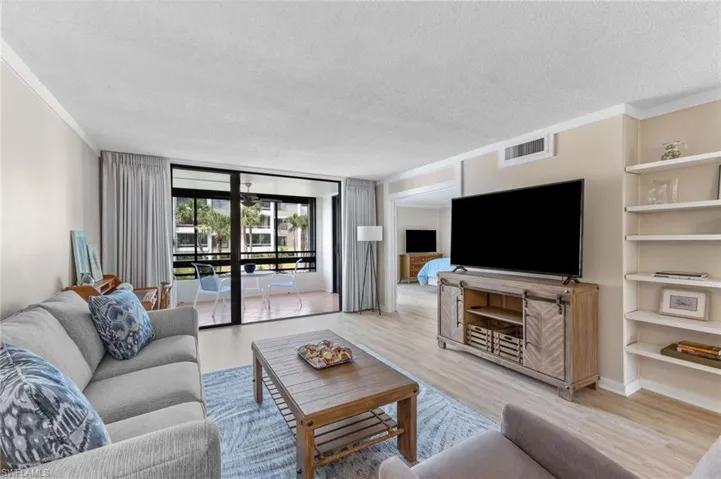 Living room featuring a wall of windows, a textured ceiling, wood finished floors, built in features, and crown molding