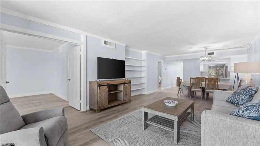 Living area featuring ornamental molding, light wood finished floors, and a chandelier