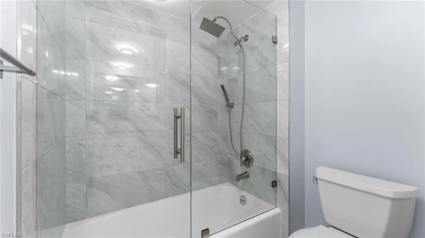 Full bathroom with combined bath / shower with glass door and toilet