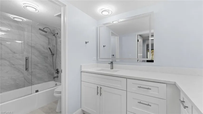 Bathroom featuring vanity and combined bath / shower with glass door