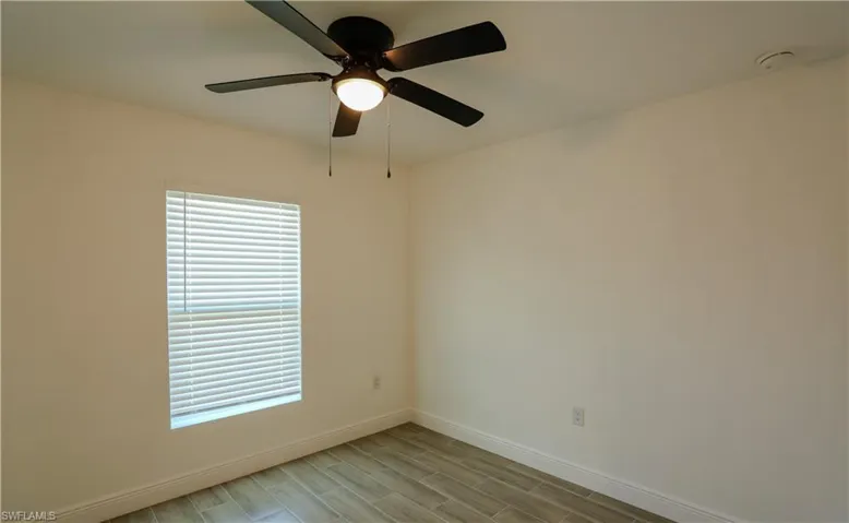 Neutral wall paint, wood-finish tile flooring, and a ceiling fan with integrated lighting
