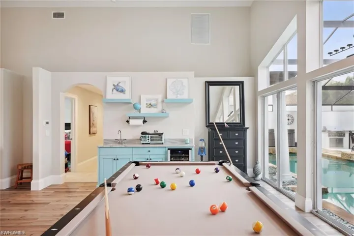 Game room with vinyl prank flooring, billiards, beverage cooler, and a healthy amount of sunlight