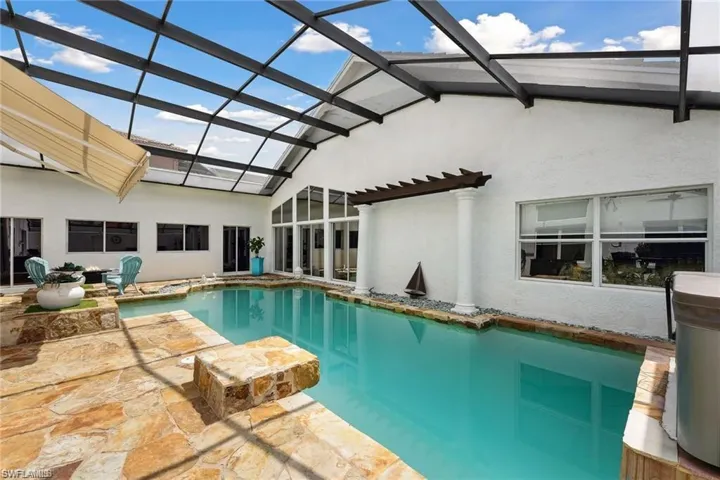 View of swimming pool featuring a patio and glass enclosure