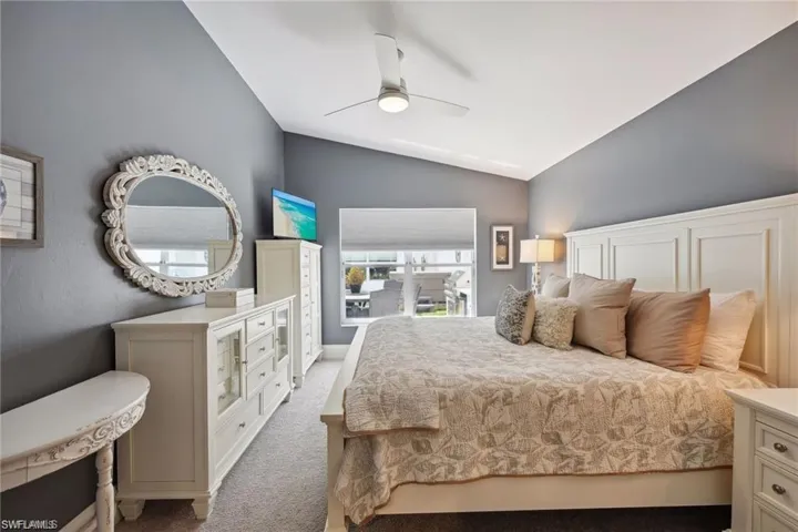Bedroom featuring vaulted ceiling, light colored carpet, and ceiling fan