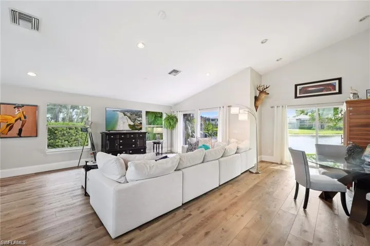 Living room with a wealth of natural light, lofted ceiling, and vinyl prank flooring.