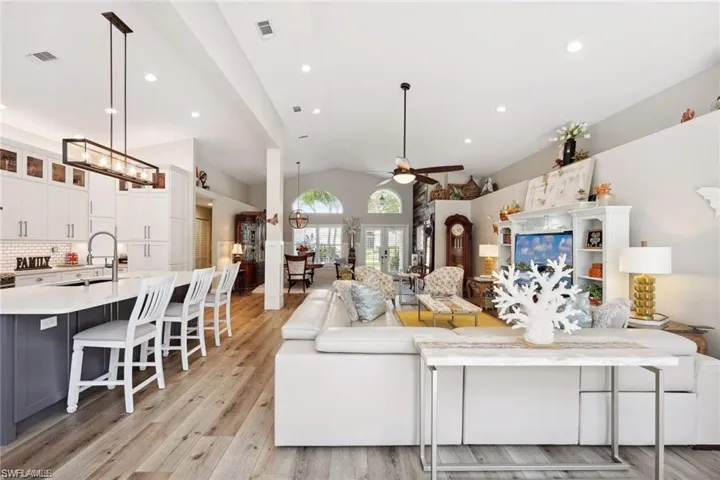 Living room featuring vinyl prank flooring, lofted ceiling, sink, and ceiling fan