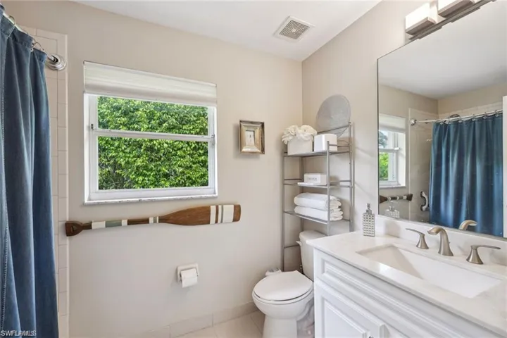 Bathroom with vanity, toilet, curtained shower, and tile patterned floors