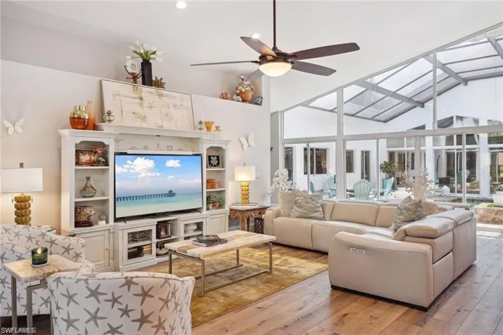 Living room with vinyl prank flooring, ceiling fan, and a high ceiling