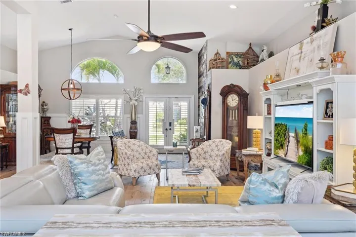 Living room with french doors, high vaulted ceiling, vinyl prank flooring and ceiling fan