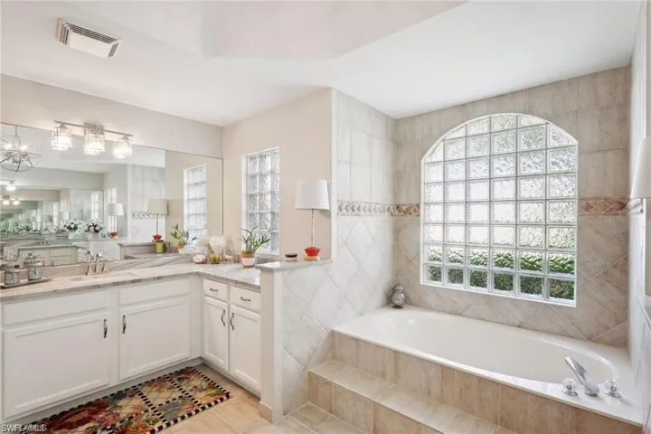 Bathroom with vanity, tile walls, tile patterned flooring, and tiled bath