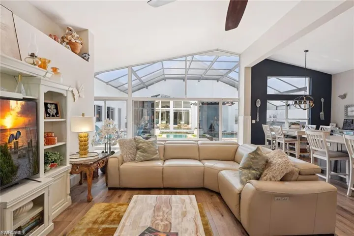 Living room featuring lofted ceiling, vinyl prank flooring, and ceiling fan