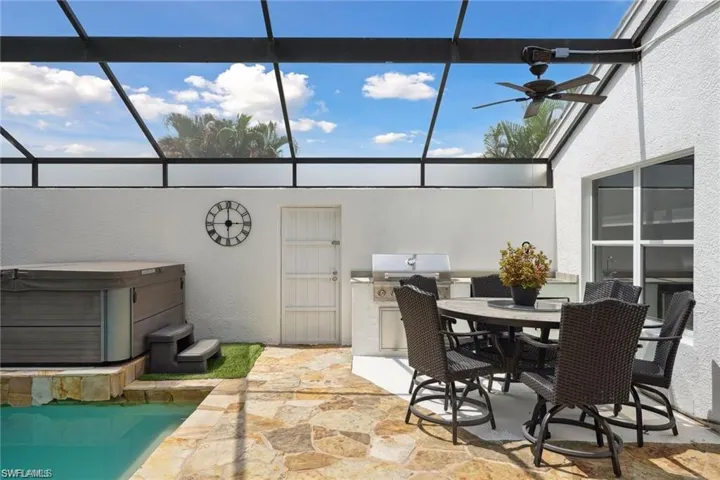 View of patio / terrace with glass enclosure, ceiling fan, and a hot tub