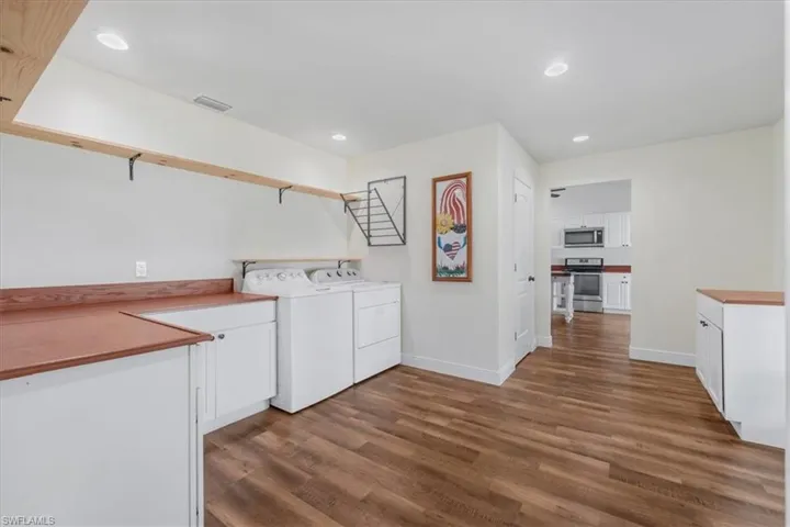 Washroom with washing machine and clothes dryer, dark wood-style floors, recessed lighting, and cabinet space