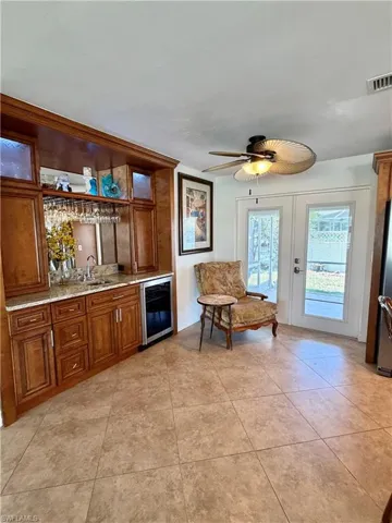 Built-in wet bar with wood cabinetry, undermount sink, and beverage refrigerator