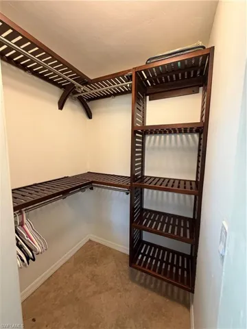 Custom closet system featuring dark wood-finish shelving and chrome hanging rods