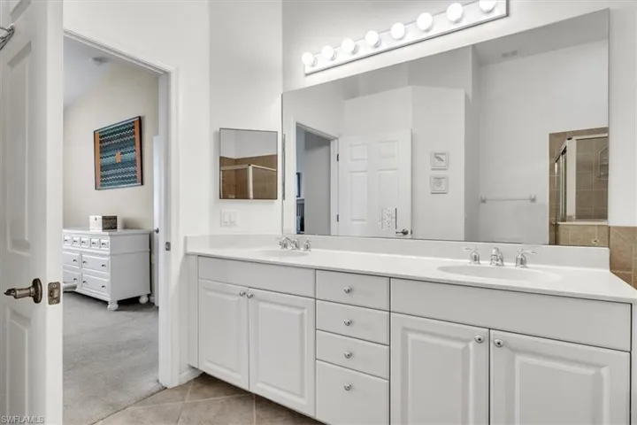 Full bath featuring light colored carpet, double vanity, light tile patterned floors, and a shower stall