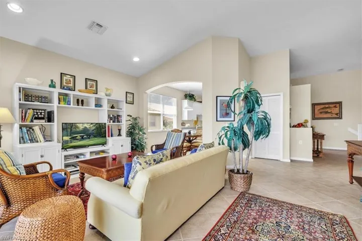 Living area featuring light tile patterned flooring, arched walkways, recessed lighting, and lofted ceiling