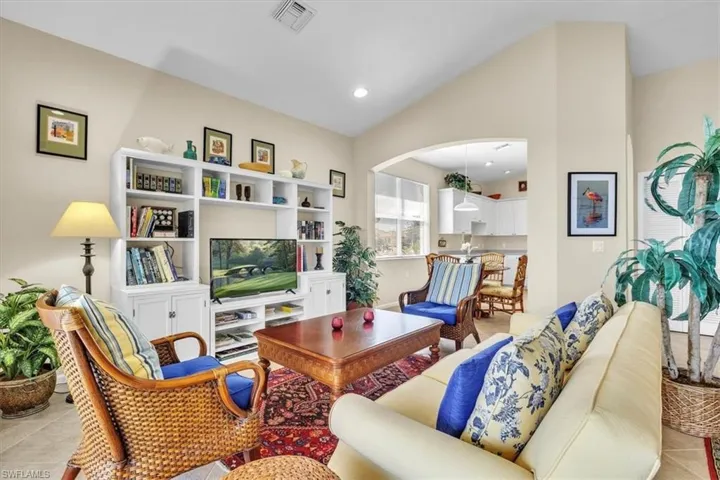 Sitting room with vaulted ceiling, light tile patterned floors, recessed lighting, and arched walkways