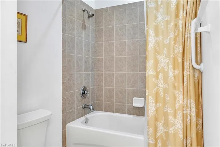 Bathroom with shower / bathtub combination with curtain and toilet