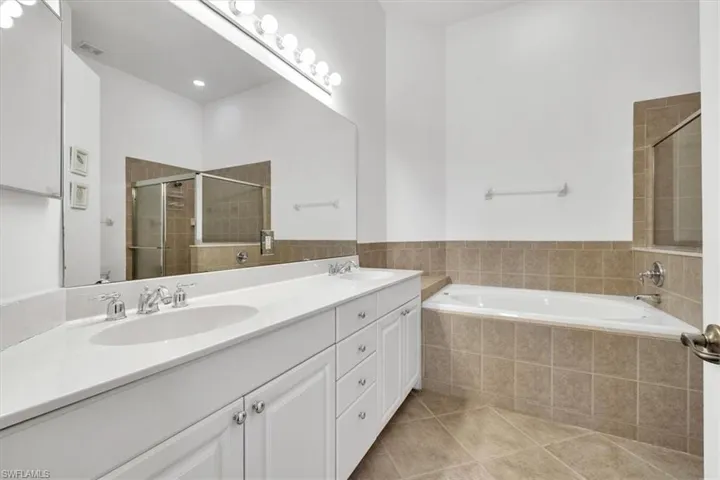 Full bathroom featuring double vanity, light tile patterned flooring, a bath, and a shower stall