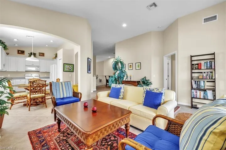 Living area with recessed lighting, light tile patterned floors, arched walkways, and a towering ceiling