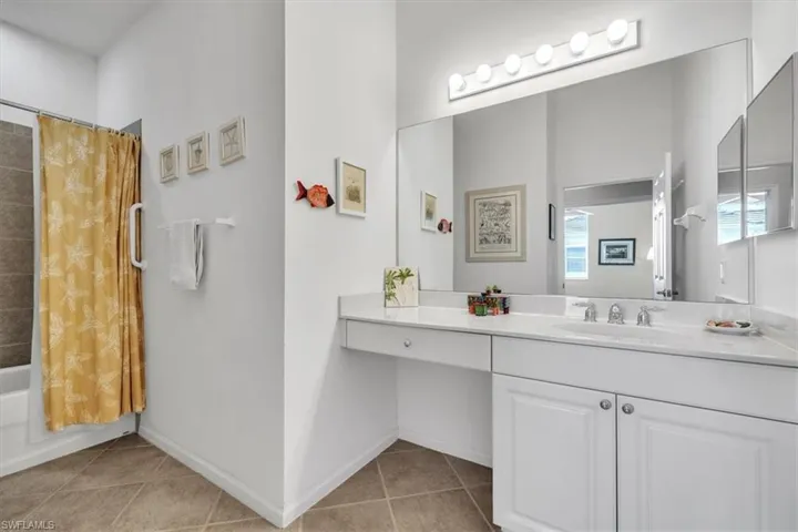 Bathroom featuring shower / tub combo, vanity, and light tile patterned flooring